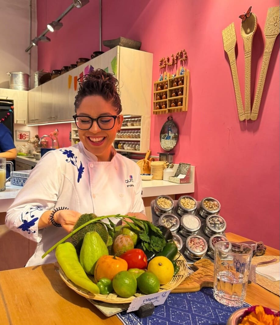 Chef holding a basket of fresh market vegetables, chiles, and herbs at a Roma Norte cooking class in Mexico City