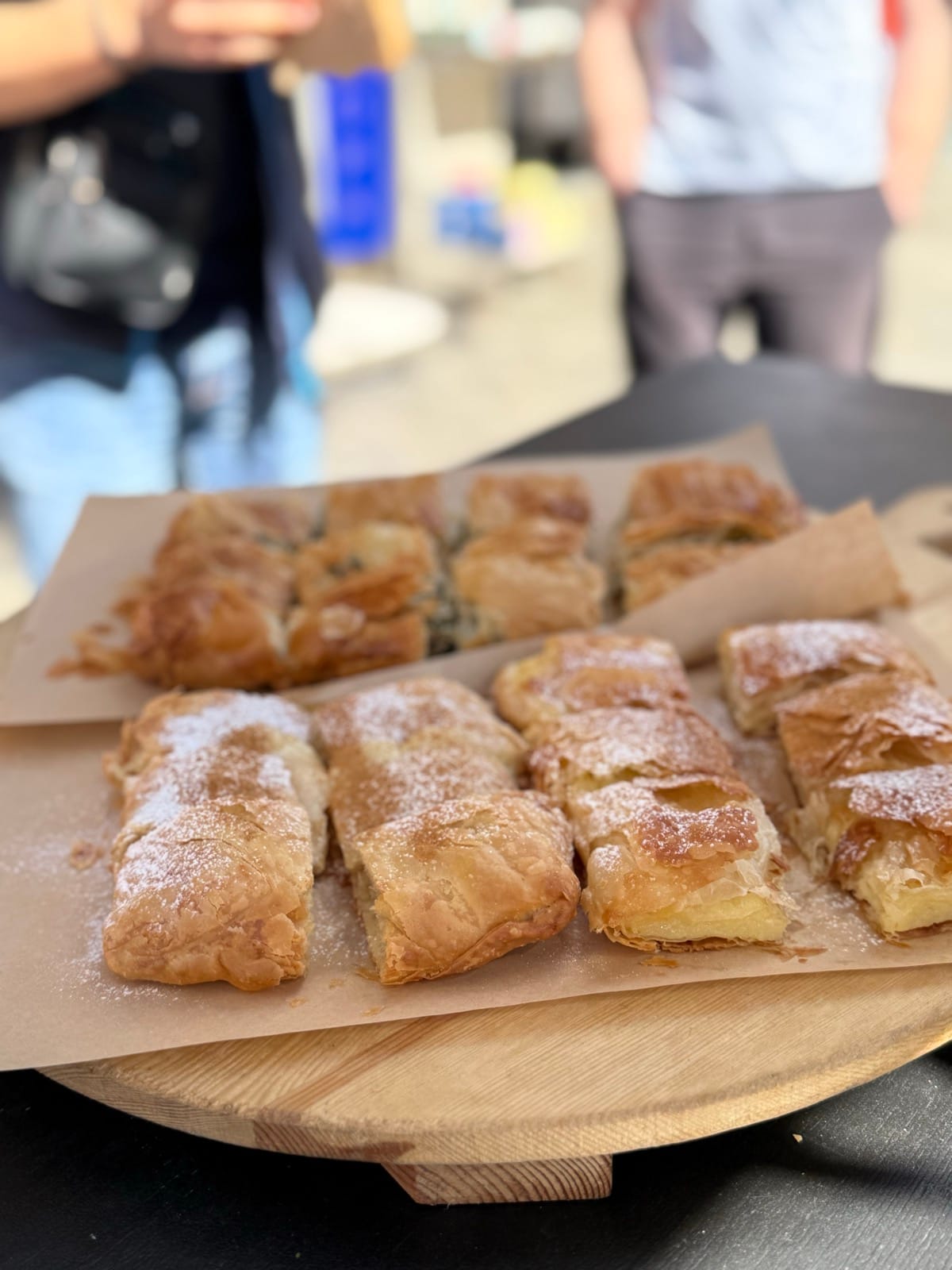 Bougatsa and pies dusted with sugar on a wooden board at Creme Royale in Athens