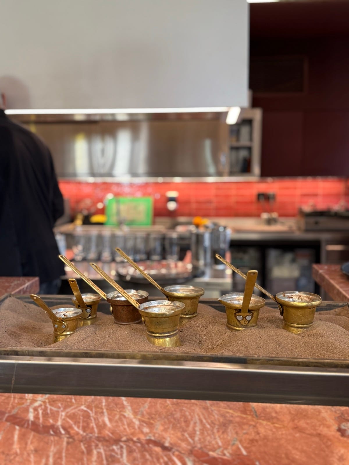 Greek coffee brewing in brass briki pots on hot sand at Mokka in Athens